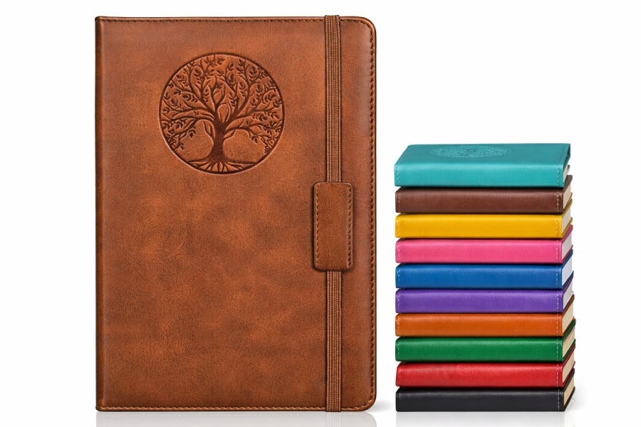 Brown leather journaling notebook with Tree of Life design and elastic strap, shown beside notebook stack of 10 available colors.